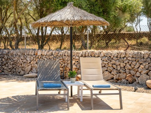 Sonnenliegen mit mallorquinischem Sonnenschirm vor der Natursteinmauer, Finca Sa Caseta, Can Picafort
