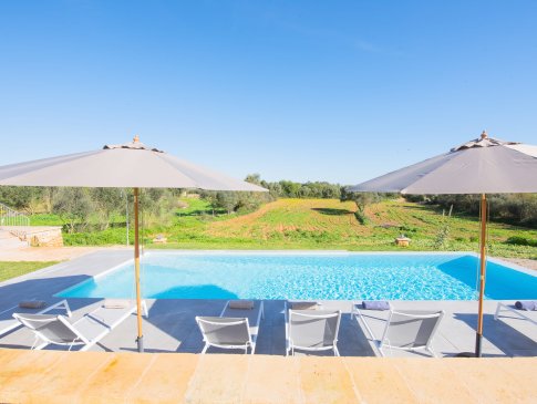Sonnenliegen und Sonnenschirme am Pool mit weitem Blick ins grüne Umland, Finca Vista Felanitx
