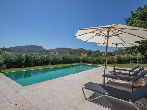 Terrasse mit Sonnenliegen und Sonnenschirmen mit Blick auf die Serra de Llevant, Finca Calma, Sant Llorenc
